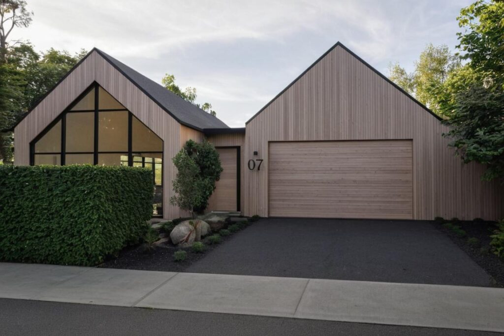Googong Residence Contemporary residential architecture in Googong featuring timber cladding, dual pitched roofs, and modern kitchen interiors.