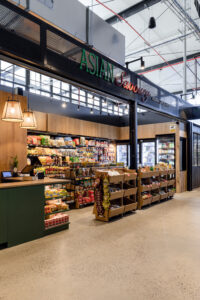 Modern grocery fitout in Canberra featuring green walls, warm timber finishes, and polished concrete flooring.